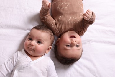 Photo of Cute twin babies resting on bed indoors, top view