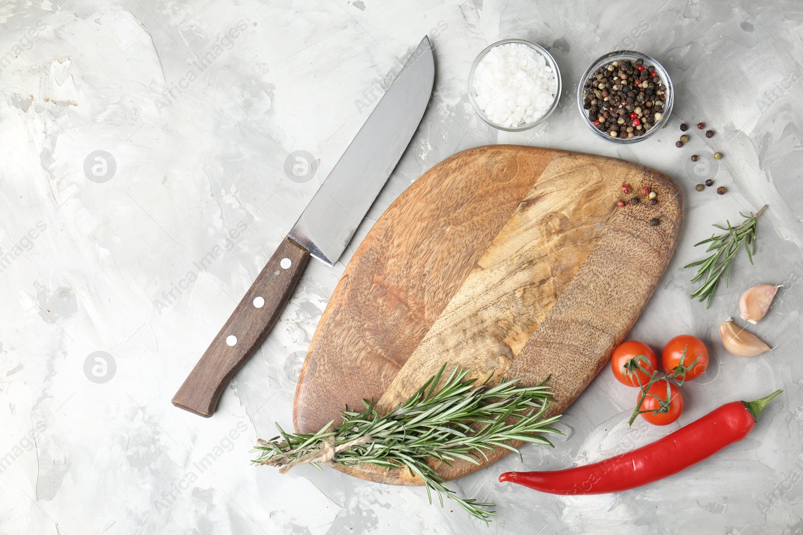 Photo of Cutting board with knife and spices on grey textured table, flat lay