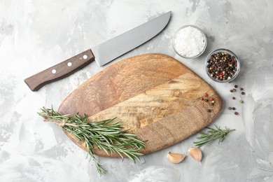 Photo of Cutting board with knife and spices on grey textured table, flat lay