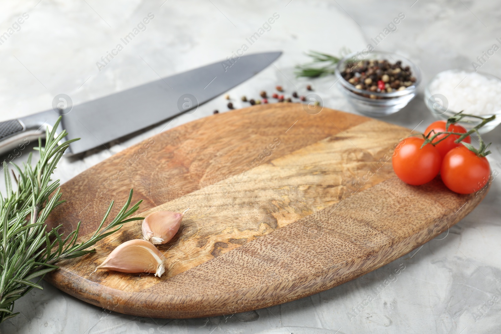 Photo of Cutting board with knife, tomatoes and spices on grey textured table, closeup