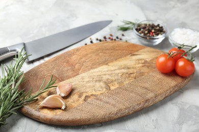 Photo of Cutting board with knife, tomatoes and spices on grey textured table, closeup