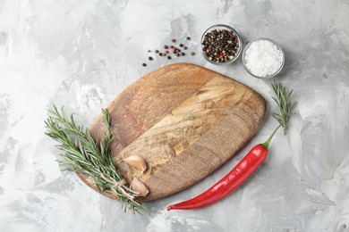 Photo of Cutting board with spices on grey textured table, flat lay