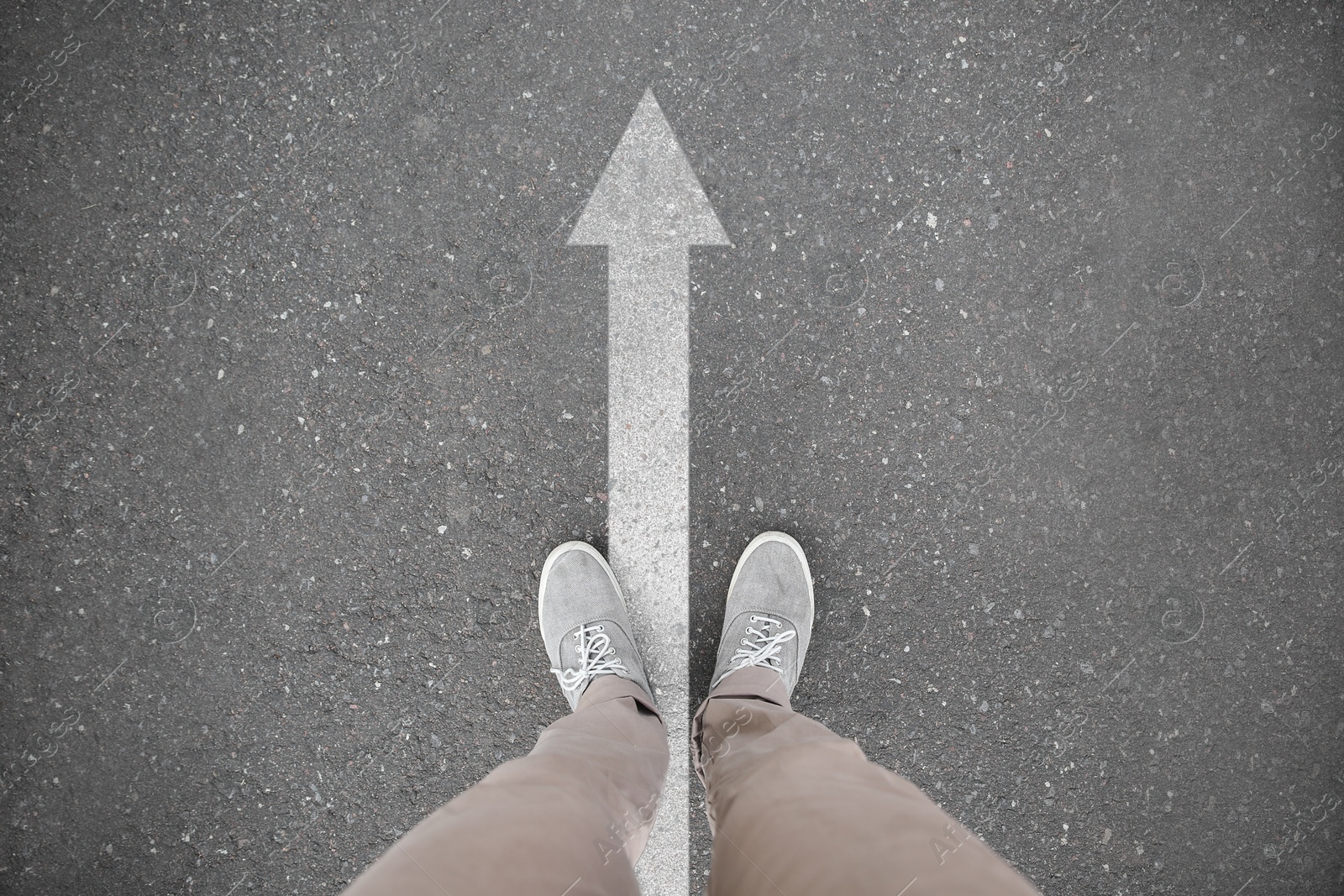 Image of Man standing near white arrow on asphalt road, closeup. Concepts of choice, decision, moving forward