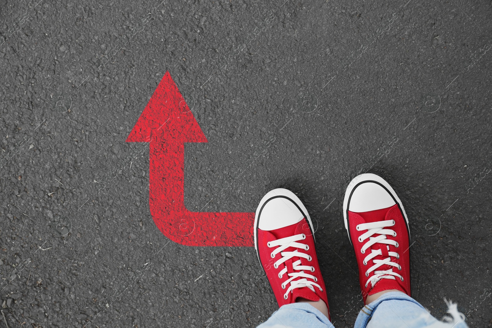 Image of Woman standing near red arrow on asphalt road, closeup. Concepts of choice, decision, moving forward