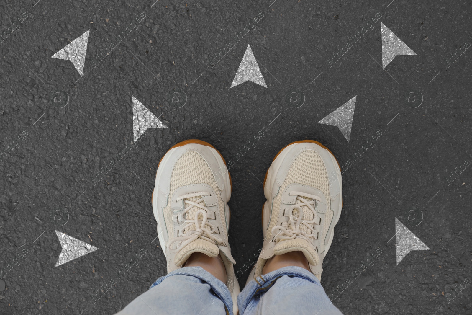 Image of Woman standing near white arrows pointing in different directions on asphalt road, closeup. Concepts of choice, decision, alternative way