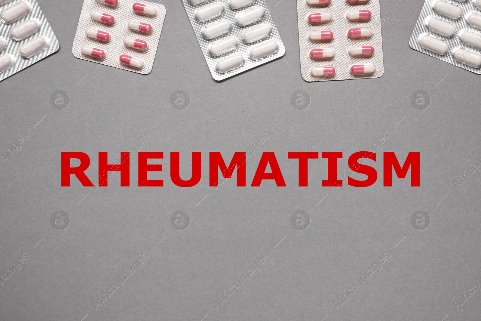 Image of Rheumatism. Different pills in blisters and word on grey background, top view