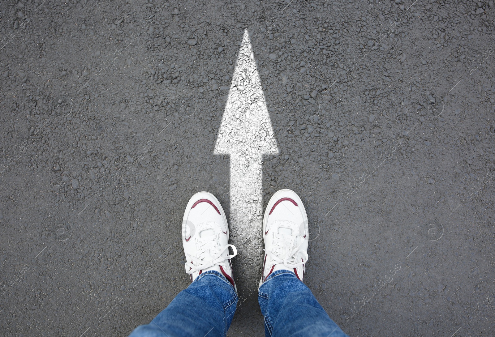 Image of Man standing near white arrow on asphalt road, closeup. Concepts of choice, decision, moving forward