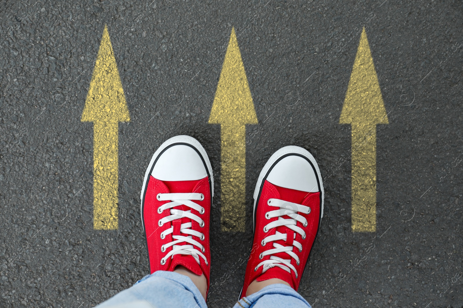 Image of Woman standing near yellow arrows on asphalt road, closeup. Concepts of choice, decision, moving forward