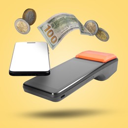 Image of Payment terminal, mobile phone, dollar and coins in air on yellow background