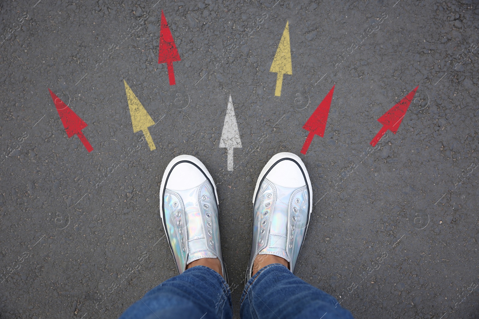 Image of Woman standing near colorful arrows on asphalt road, closeup. Concepts of choice, decision, different way, alternative