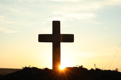 Silhouette of Christian cross outdoors at sunrise. Religion concept