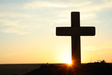 Silhouette of Christian cross outdoors at sunrise, space for text. Religion concept