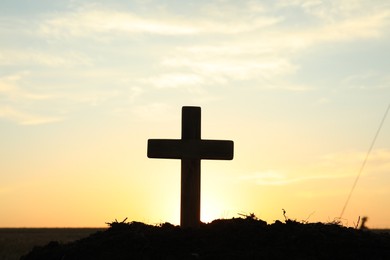 Photo of Silhouette of Christian cross outdoors at sunrise. Religion concept