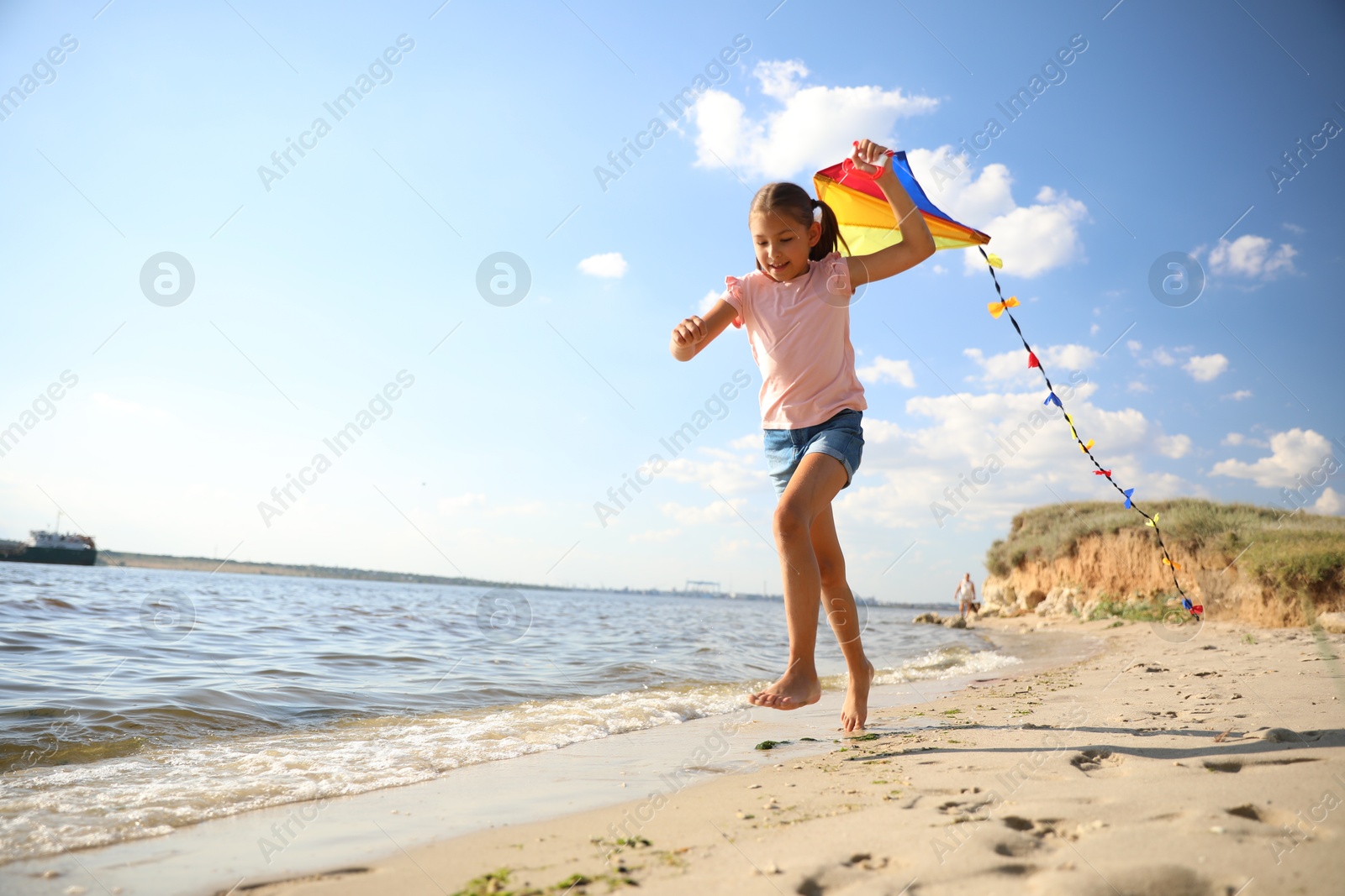 Photo of Cute little child with kite running on beach near sea. Spending time in nature