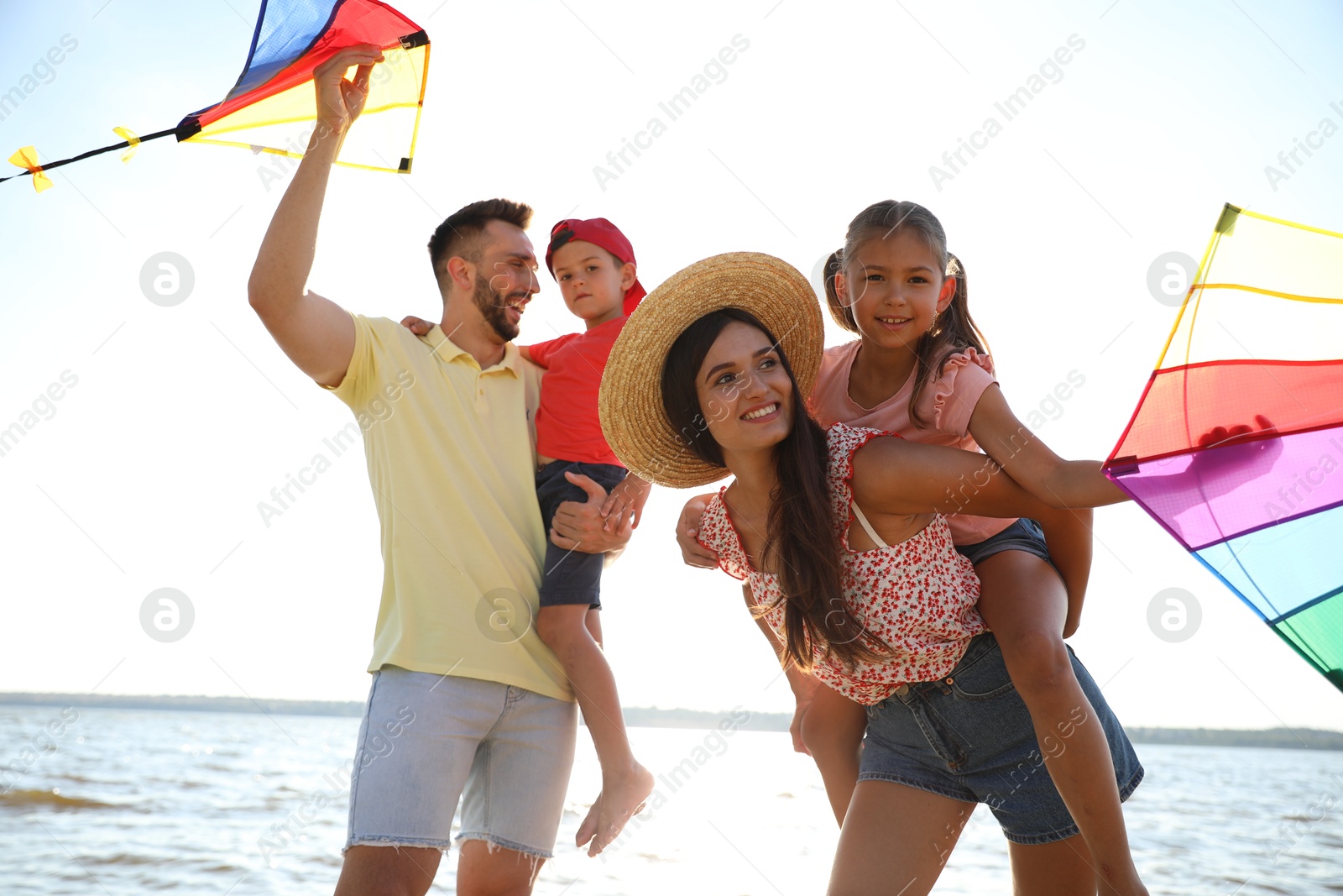 Photo of Happy parents and their children playing with kites near sea. Spending time in nature