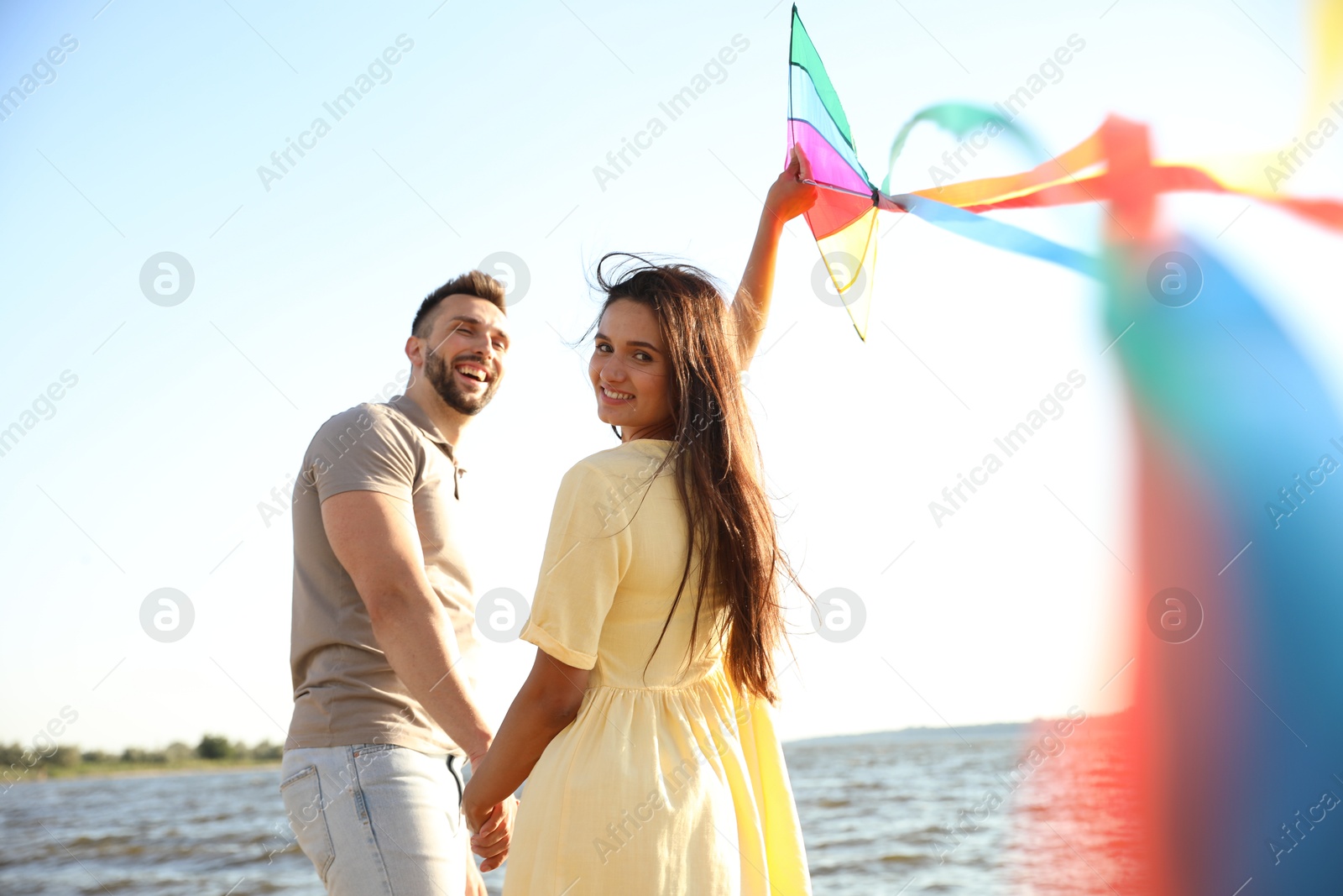 Photo of Happy couple playing with kite near sea. Spending time in nature