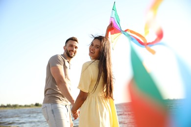 Photo of Happy couple playing with kite near sea. Spending time in nature