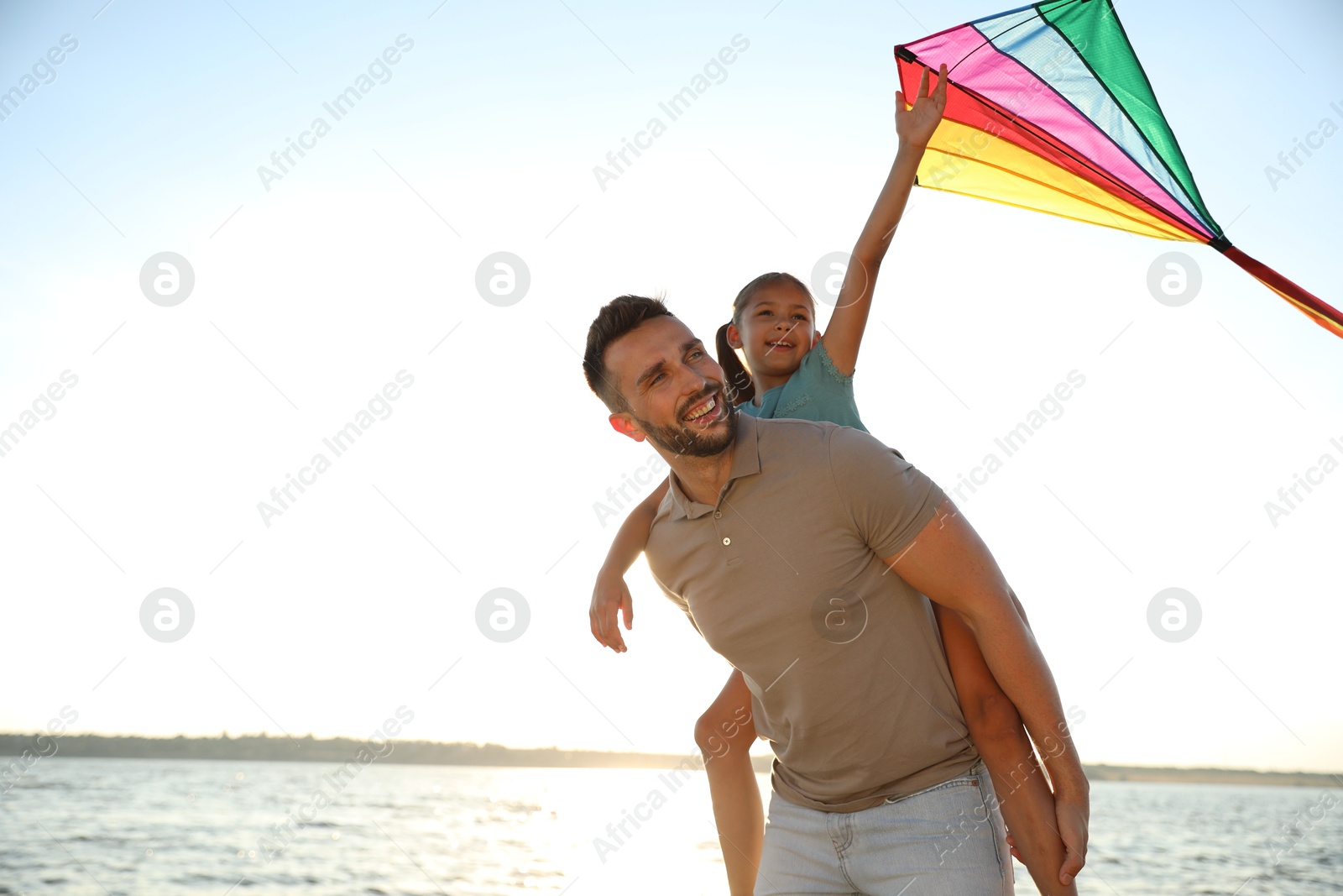 Photo of Happy father and his child playing with kite near sea. Spending time in nature