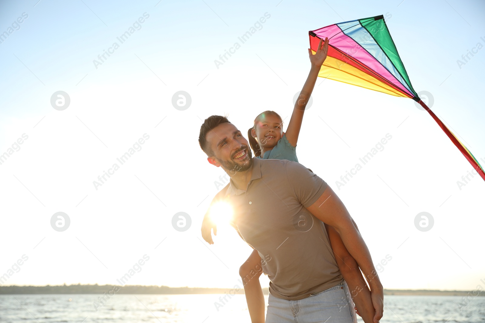 Photo of Happy father and his child playing with kite near sea. Spending time in nature