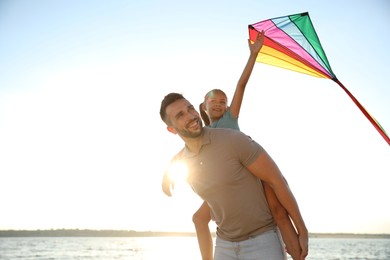 Happy father and his child playing with kite near sea. Spending time in nature