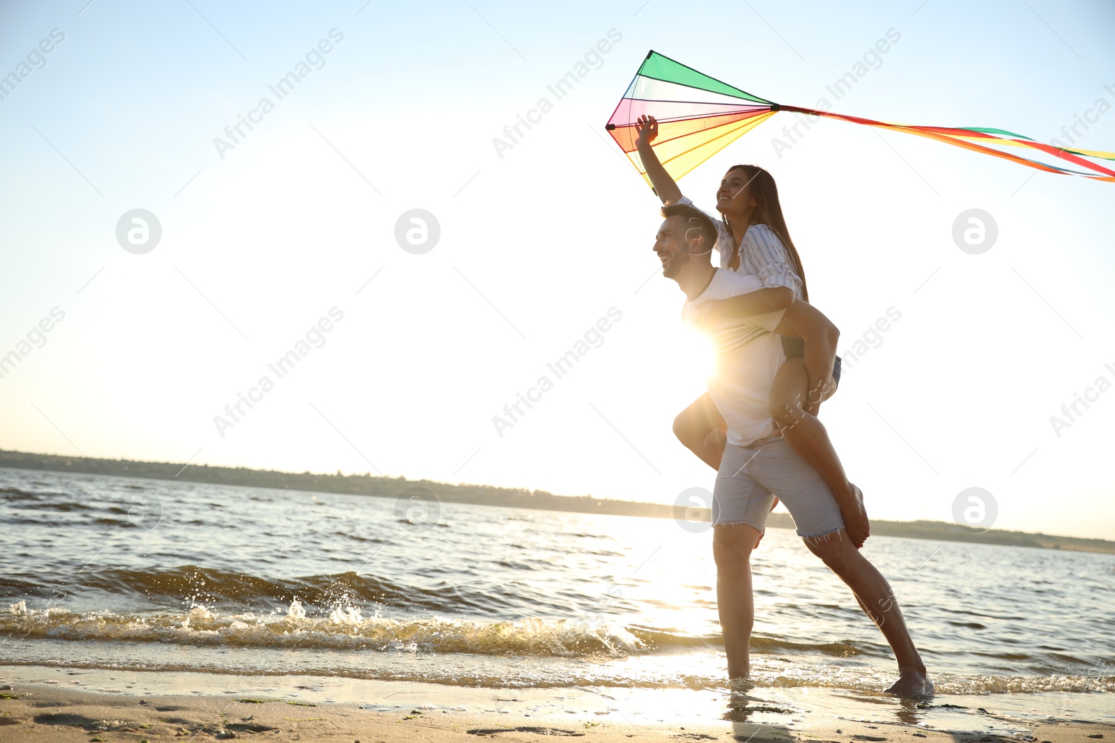 Photo of Happy couple playing with kite on beach near sea. Spending time in nature