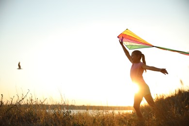 Photo of Cute little child with kite running outdoors at sunset. Spending time in nature