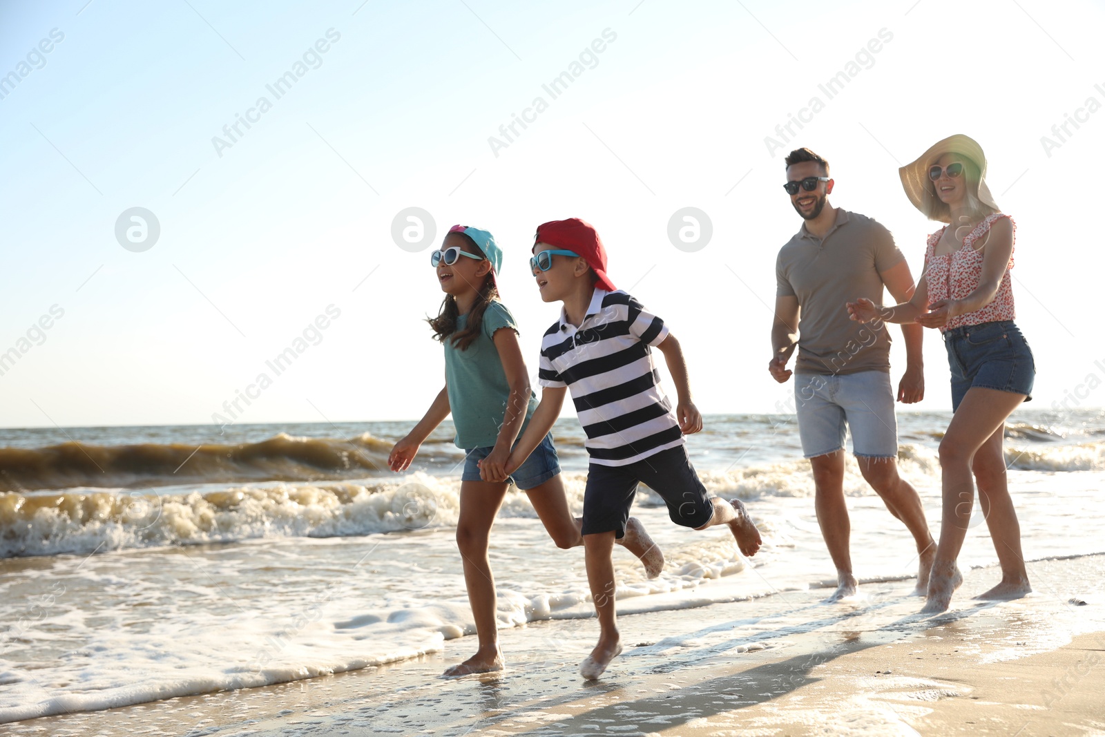 Photo of Happy family running on sandy beach near sea