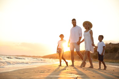 Photo of Happy family on sandy beach near sea at sunset