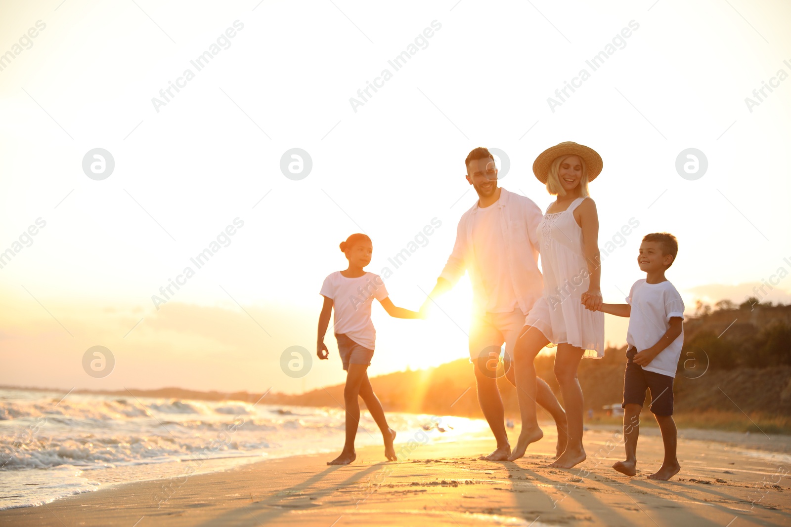 Photo of Happy family on sandy beach near sea at sunset