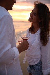 Photo of Couple with glasses of wine on beach at sunset