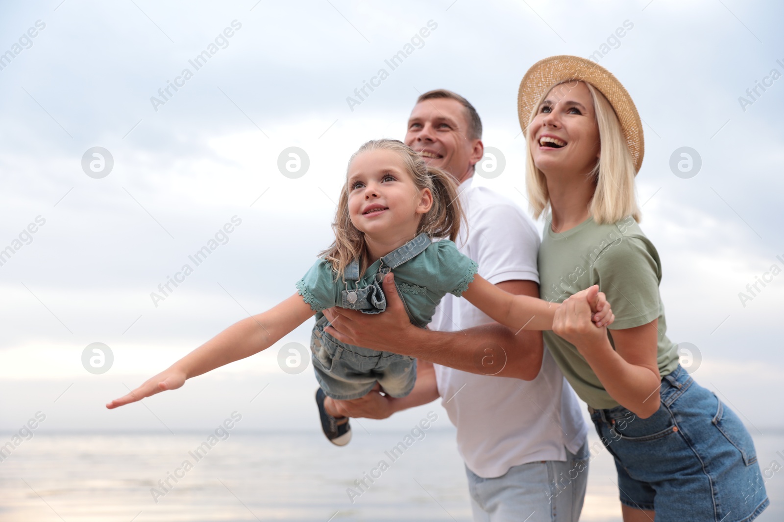 Photo of Happy family spending time together near sea on sunny summer day