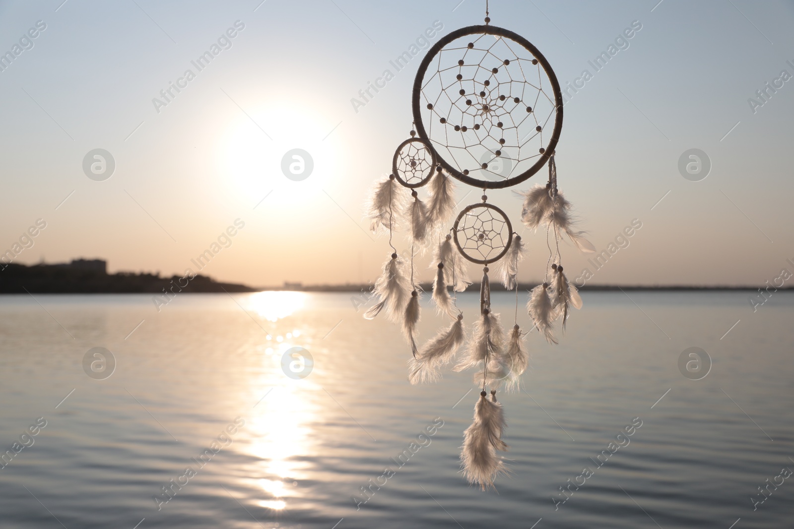 Photo of Beautiful handmade dream catcher near river at sunset. Space for text