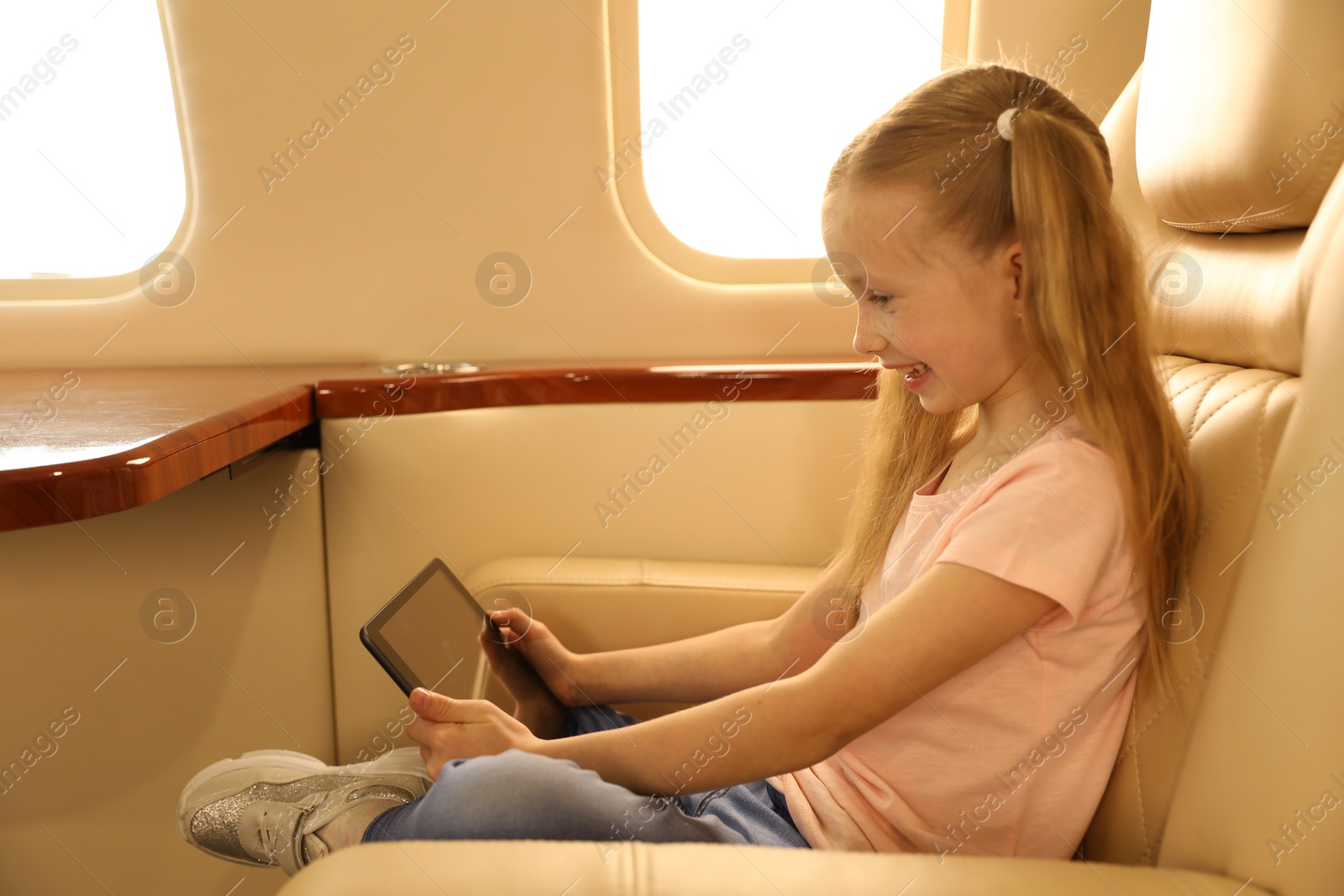 Photo of Cute little girl using tablet in airplane during flight