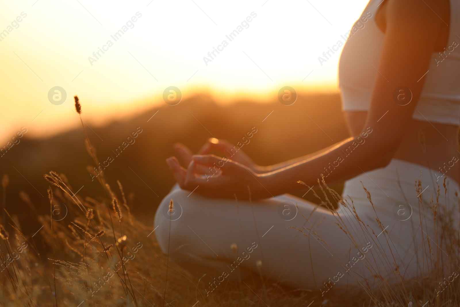 Photo of Woman meditating outdoors at sunset, closeup view