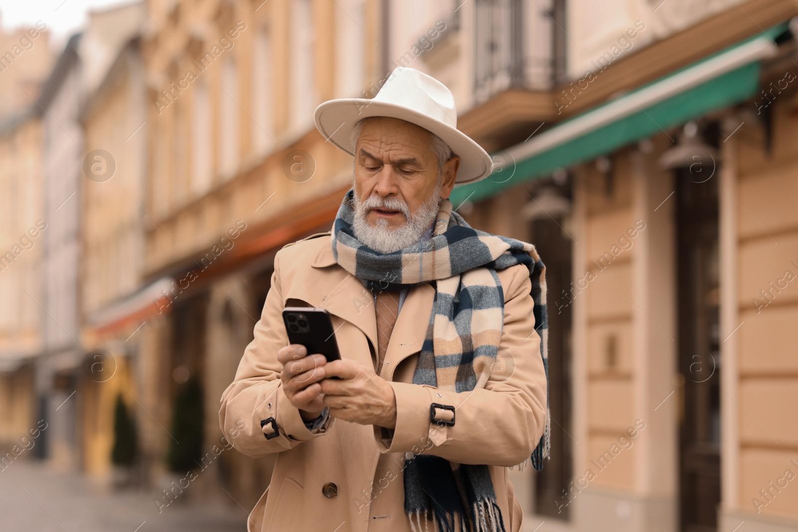 Photo of Stylish senior man with smartphone on city street