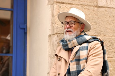 Photo of Stylish bearded senior man on city street. Space for text