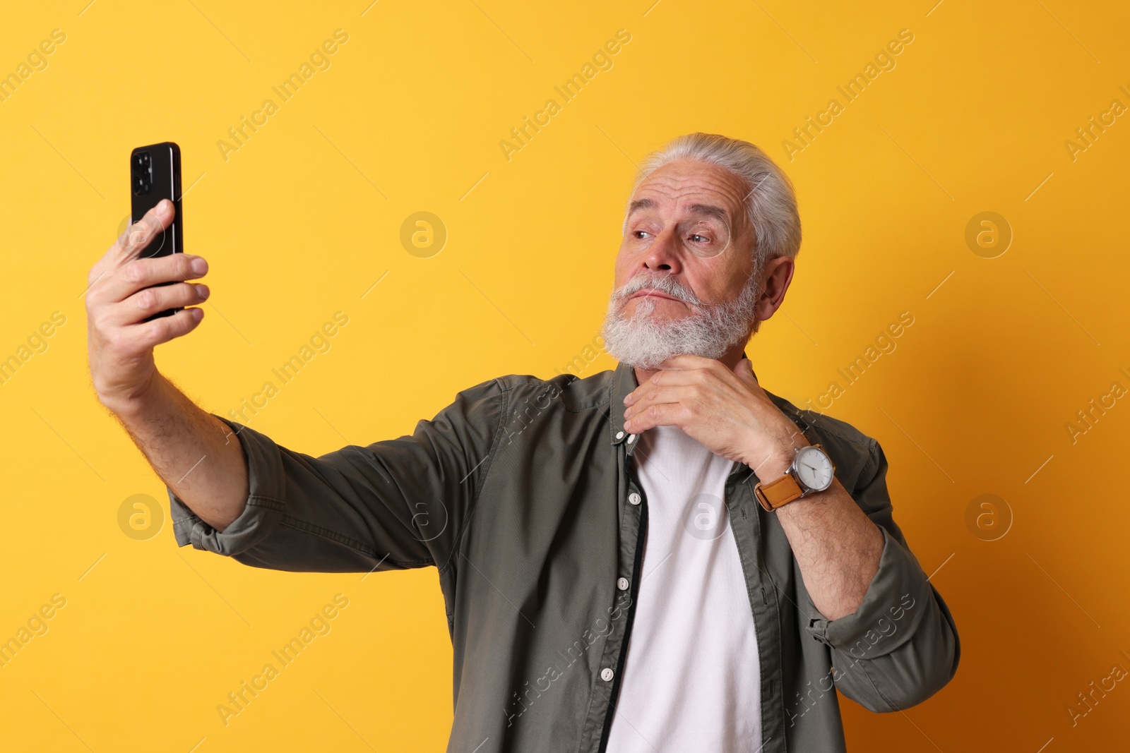 Photo of Senior man taking selfie on orange background