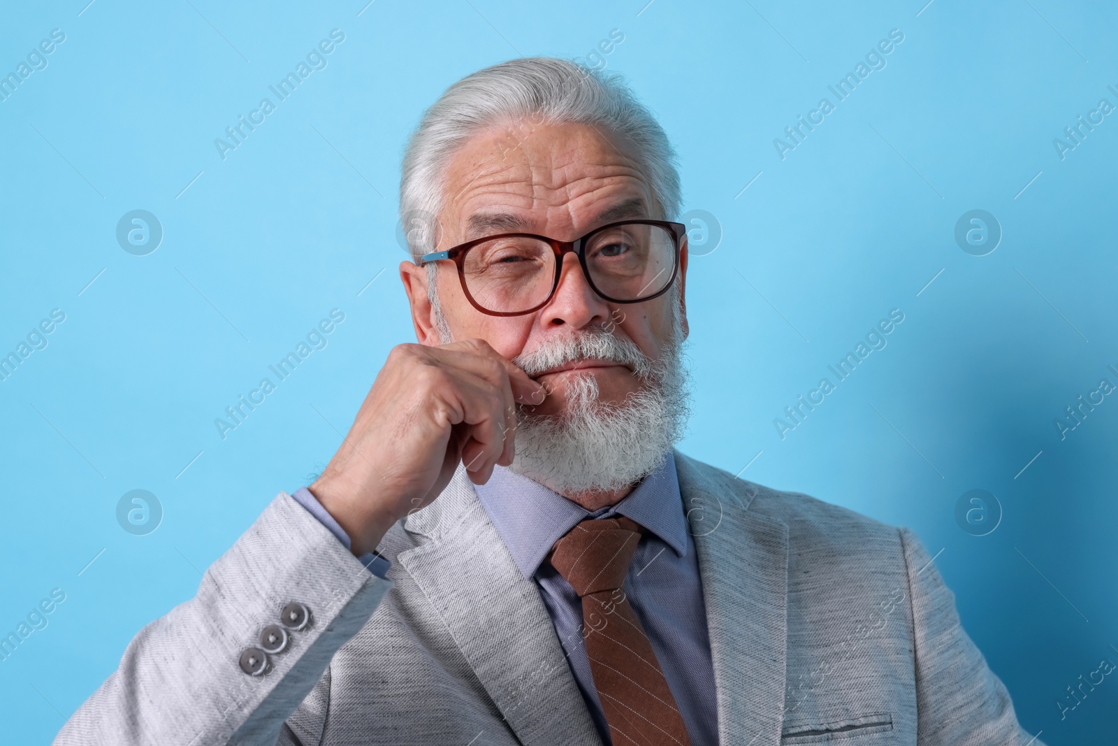 Photo of Portrait of serious senior man with silver beard on light blue background