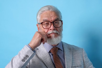 Photo of Portrait of serious senior man with silver beard on light blue background