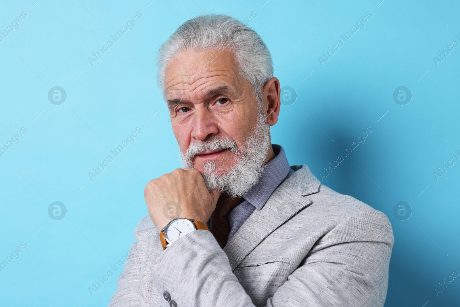 Photo of Portrait of senior man with gray beard on light blue background