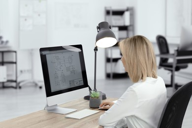 Photo of Technician making digital engineering drawing on computer at desk in office