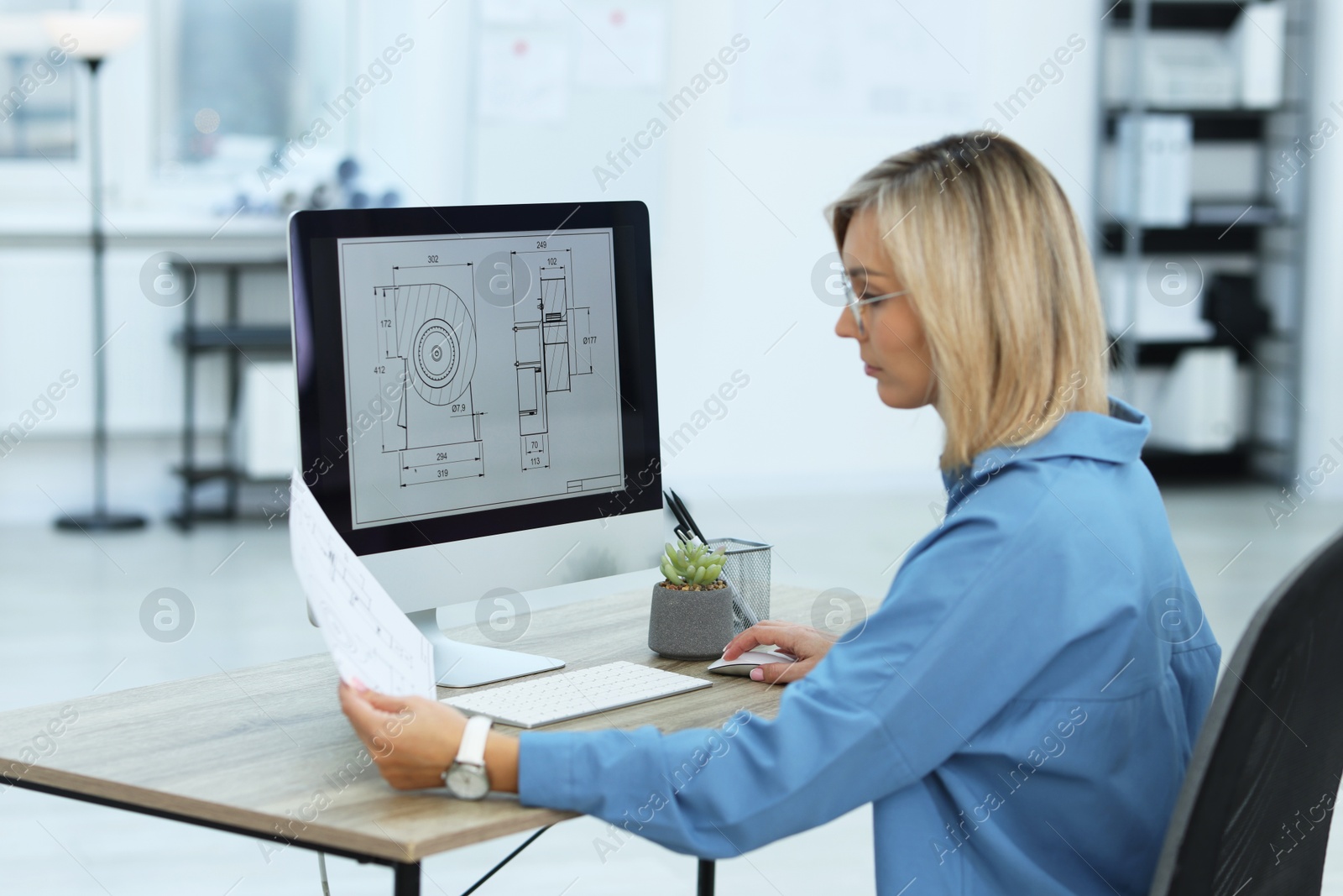 Photo of Technician making digital engineering drawing on computer at desk in office