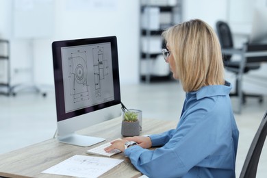 Photo of Technician making digital engineering drawing on computer at desk in office