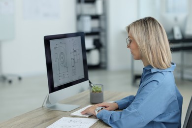 Photo of Technician making digital engineering drawing on computer at desk in office