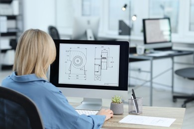 Photo of Technician making digital engineering drawing on computer at desk in office, back view