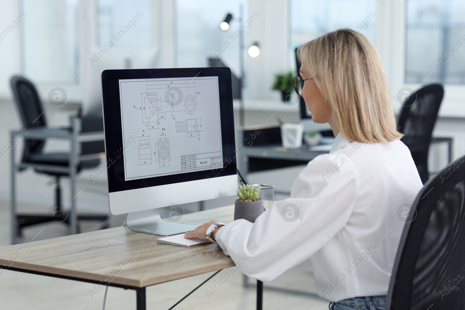 Photo of Technician making digital engineering drawing on computer at desk in office