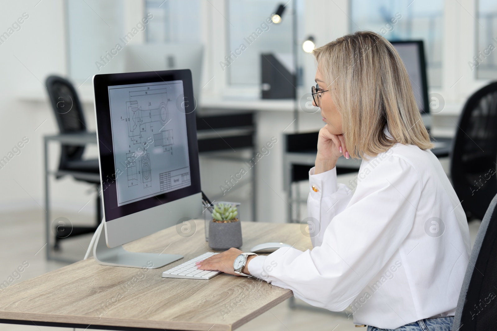 Photo of Technician making digital engineering drawing on computer at desk in office