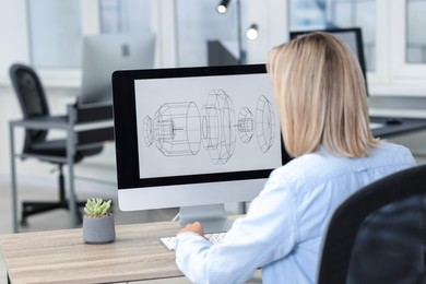 Photo of Technician making digital engineering drawing on computer at desk in office, back view