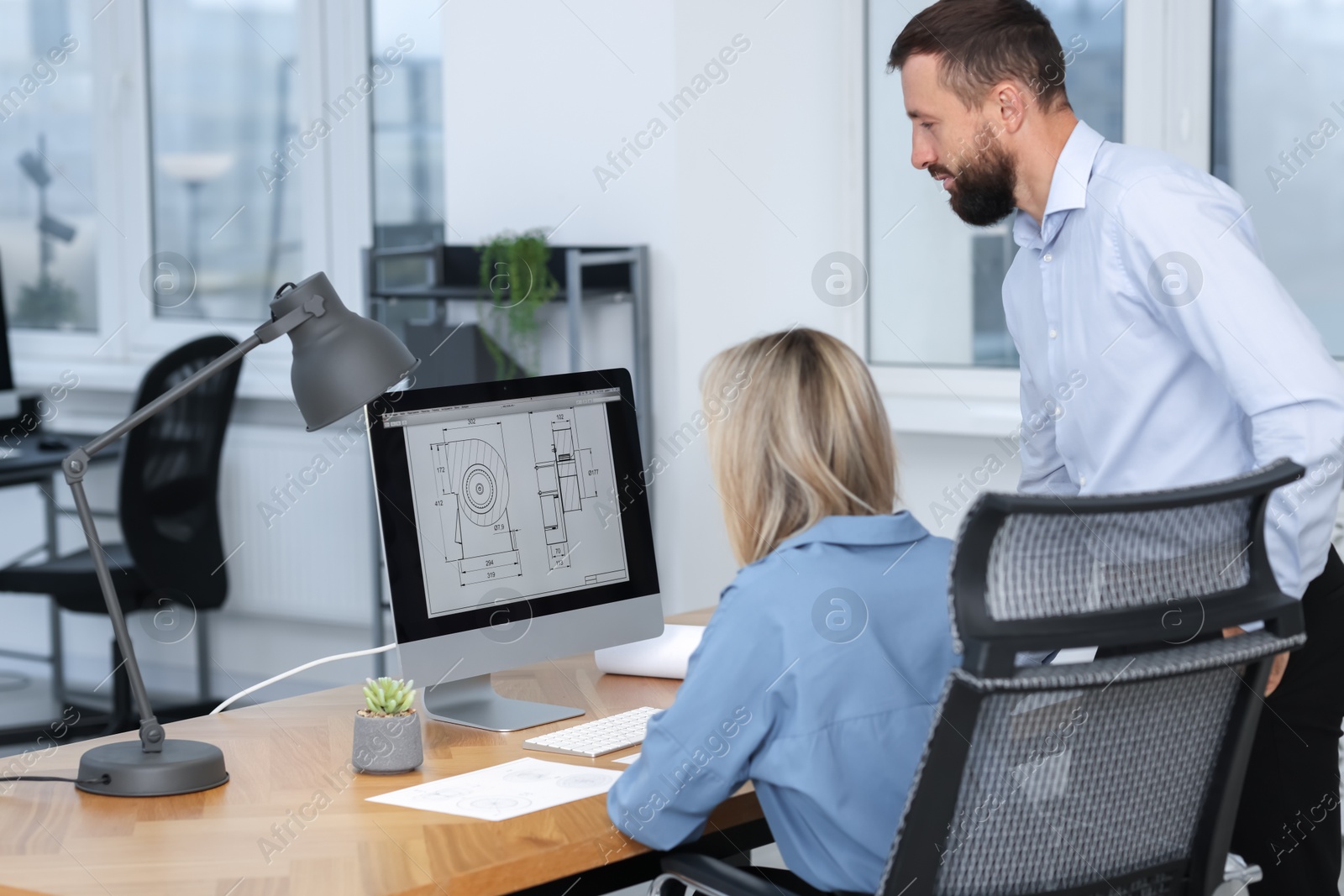 Photo of Technicians making digital engineering drawing on computer at desk in office