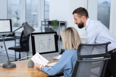 Photo of Technicians making digital engineering drawing on computer at desk in office